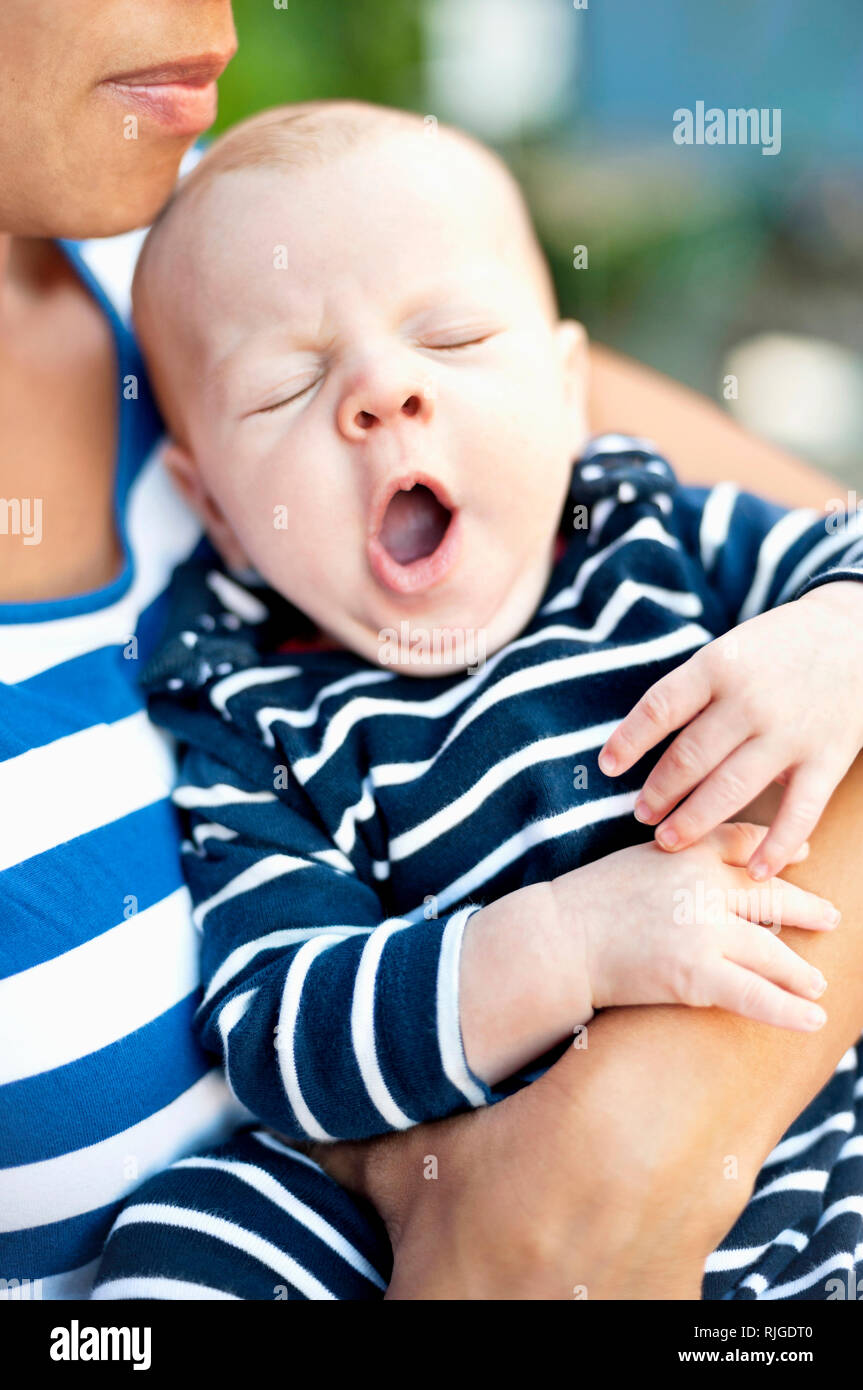 Mother holding yawning baby boy Stock Photo