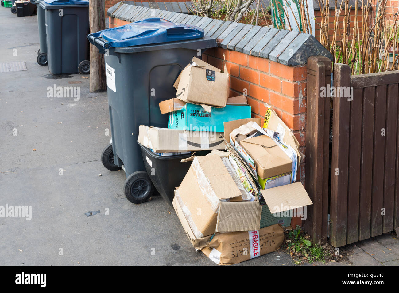 Cardboard boxes piled up beside recycling bin on the pavement during