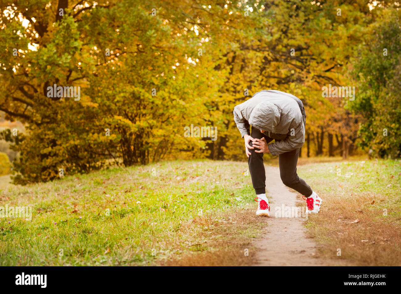 running along a park path, healthcare and problem concept - close-up of an unhappy person suffering from pain in the leg or knee outdoors Stock Photo