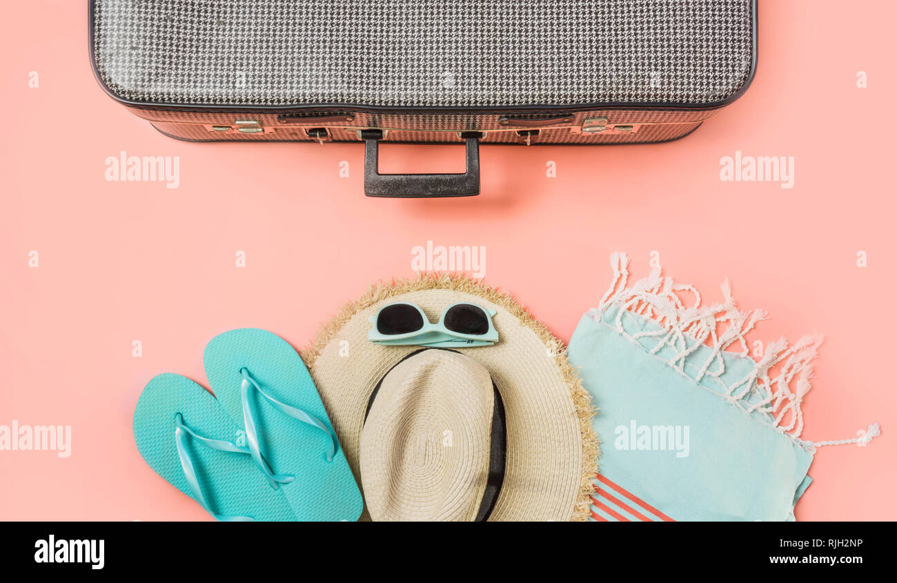 Suitcase with female outfit for beach on pastel pink background. Top view with copy space. Summer tropical vacatons. Stock Photo