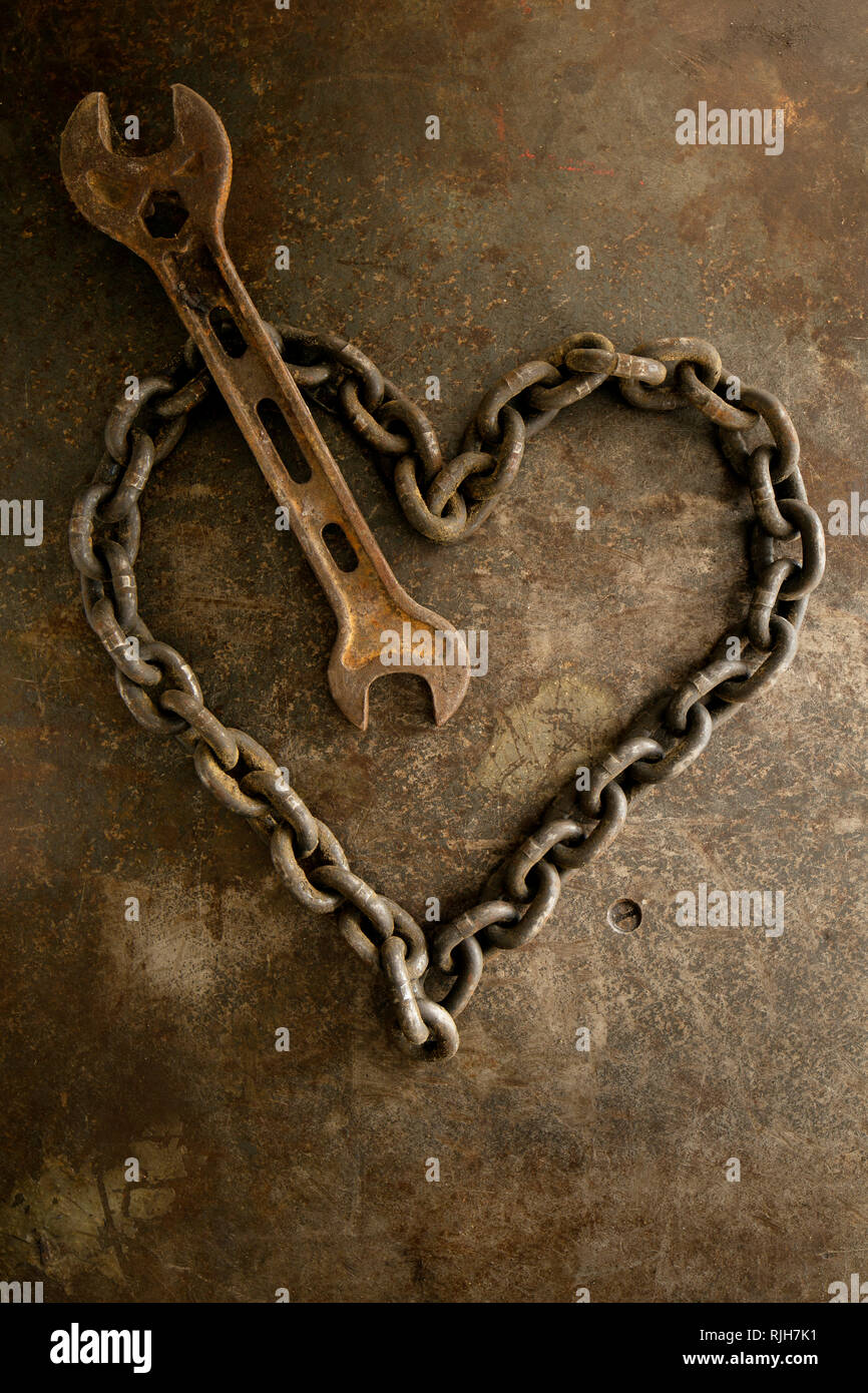 Rusty chain in heart shape and spanner Stock Photo