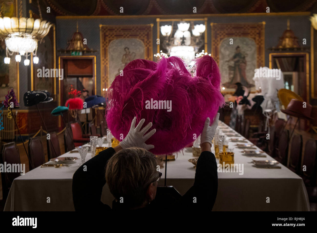 A member of staff adjusts a hat designed for Lady Gaga (2012) by milliner Stephen Jones at the launch of Chinoiserie-on-Sea exhibition which will fill the rooms of the Royal Pavilion, Brighton, East Sussex, with dozens of hats made by Jones throughout his 40-year career. Stock Photo