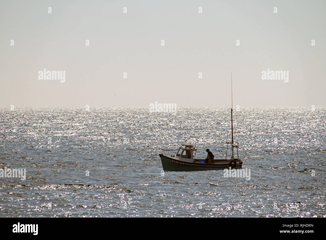 Lone fisherman off Looe, seaside town in Cornwall UK Stock Photo