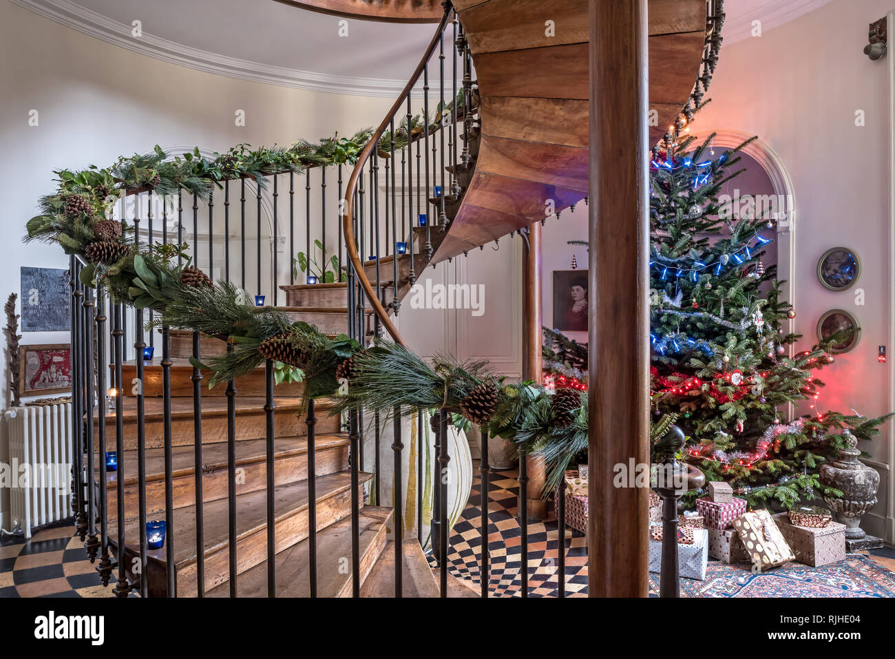 Christmas tree in hallway with walnut pillars support floating cantilevered stairs Stock Photo