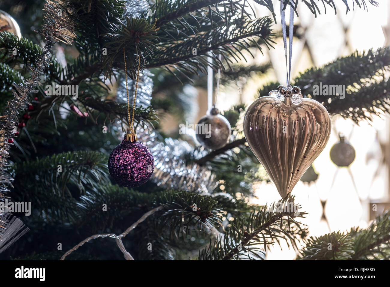 Gold heart shaped and glitter bauble hanging on Christmas tree Stock Photo