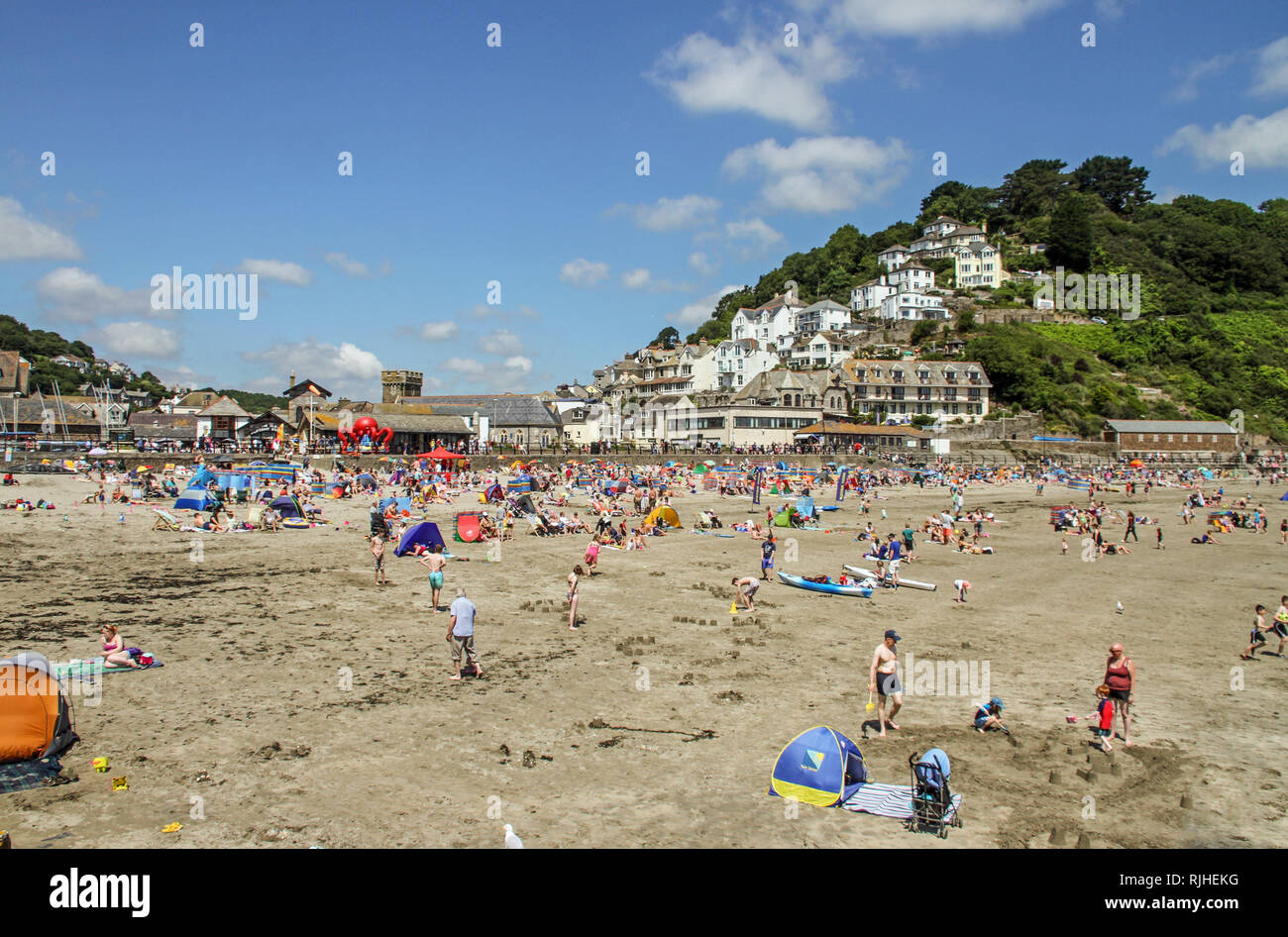 Visitors enjoy the sunshine, sand and sea on the popular beach at East Looe in Cornwall. Stock Photo