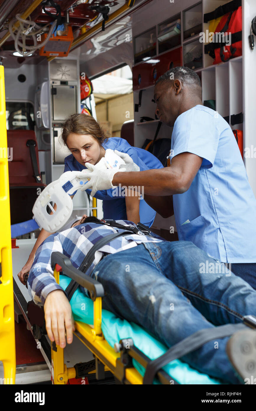 Ambulance team laying patient on stretcher in ambulance car Stock Photo ...