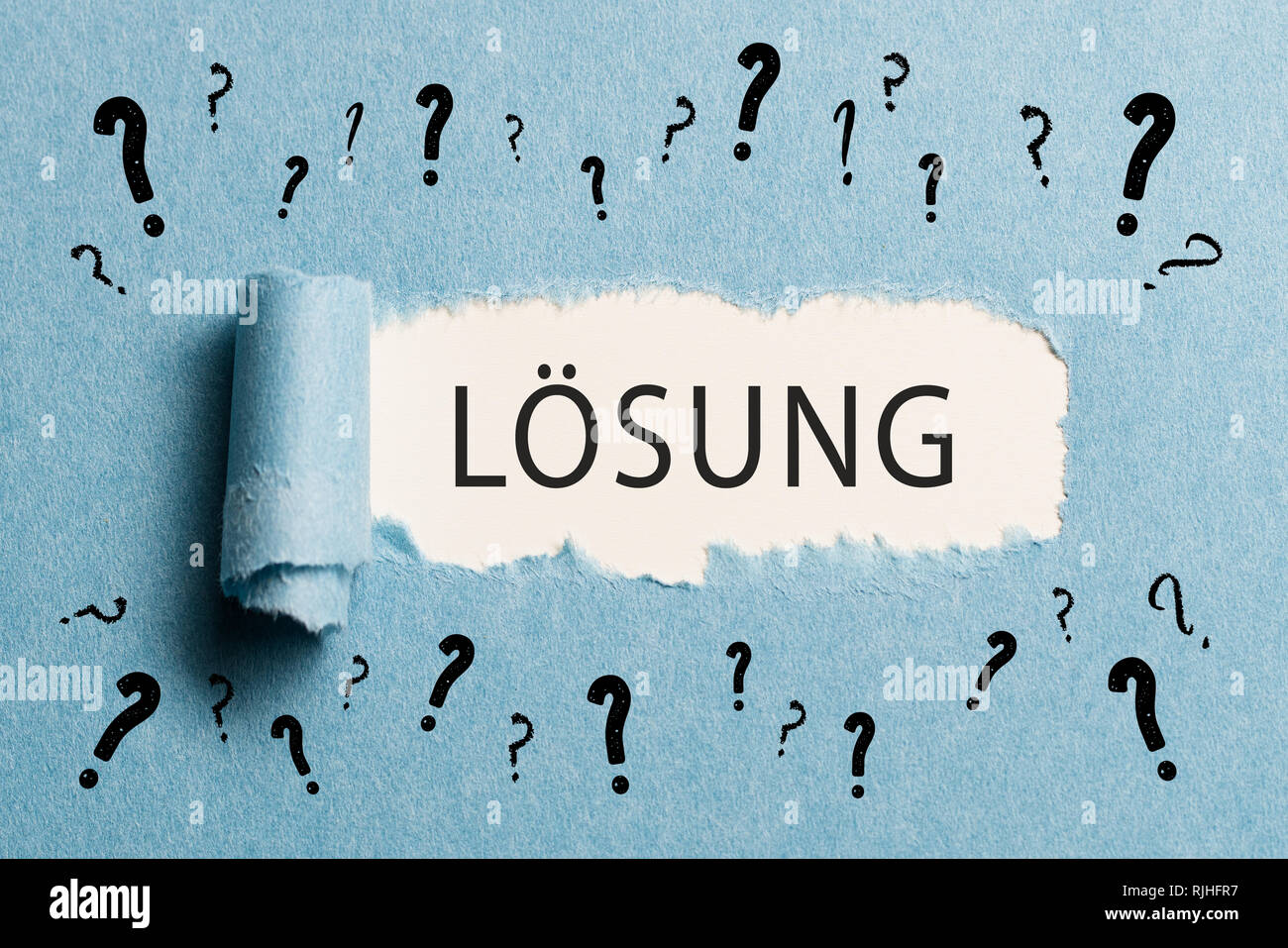 torn paper revealing the word "solution" in German Stock Photo Alamy