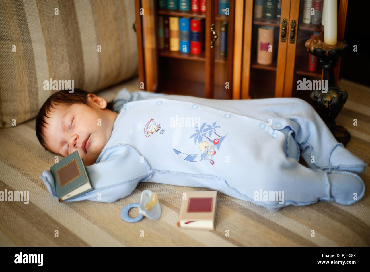 The kid fell asleep on the couch near the closet with books Stock Photo