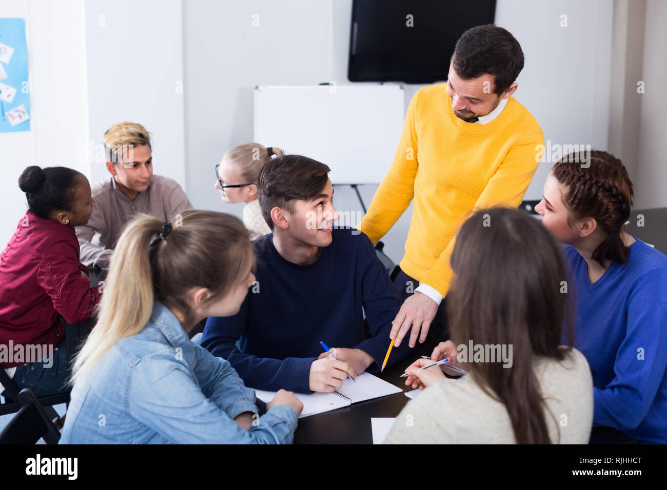 Man teacher is monitoring students during exam in class. Stock Photo