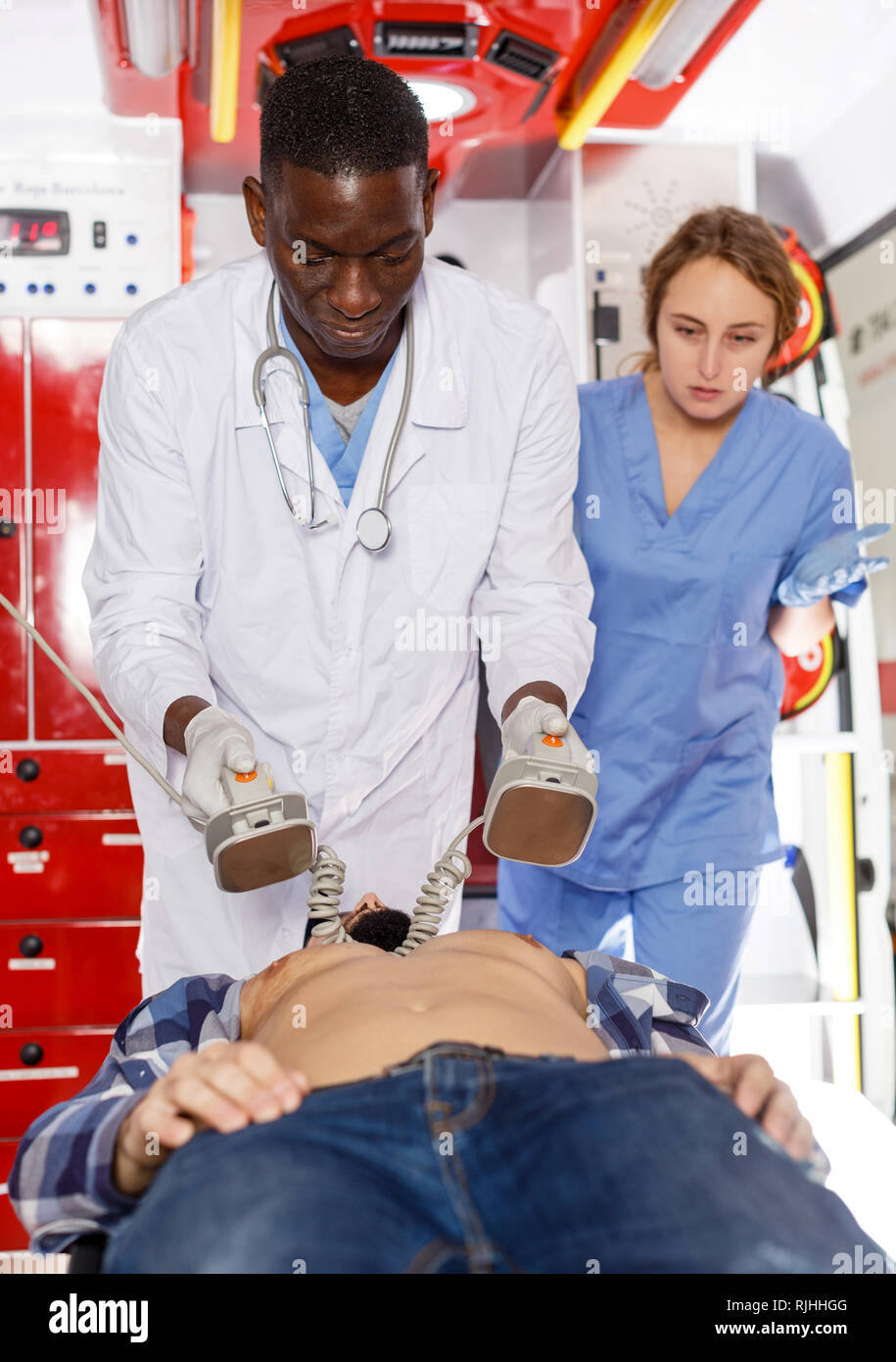 Afro emergency doctor using defibrillator for providing medical care to