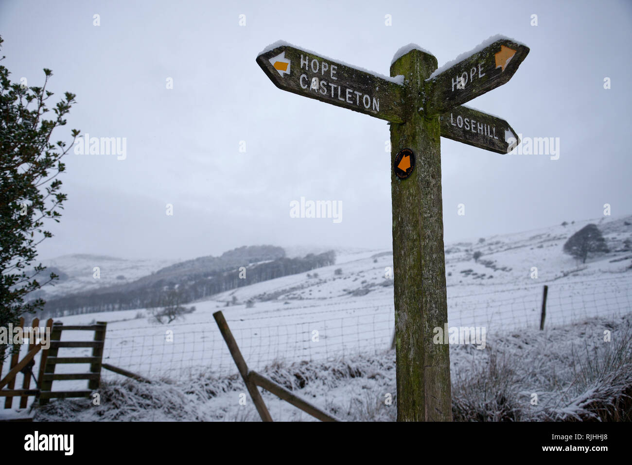Snowy dawn in the Peak District National Park, England. Twilight light with footpath sign. Hope, Castleton and Losehill signage. Stock Photo