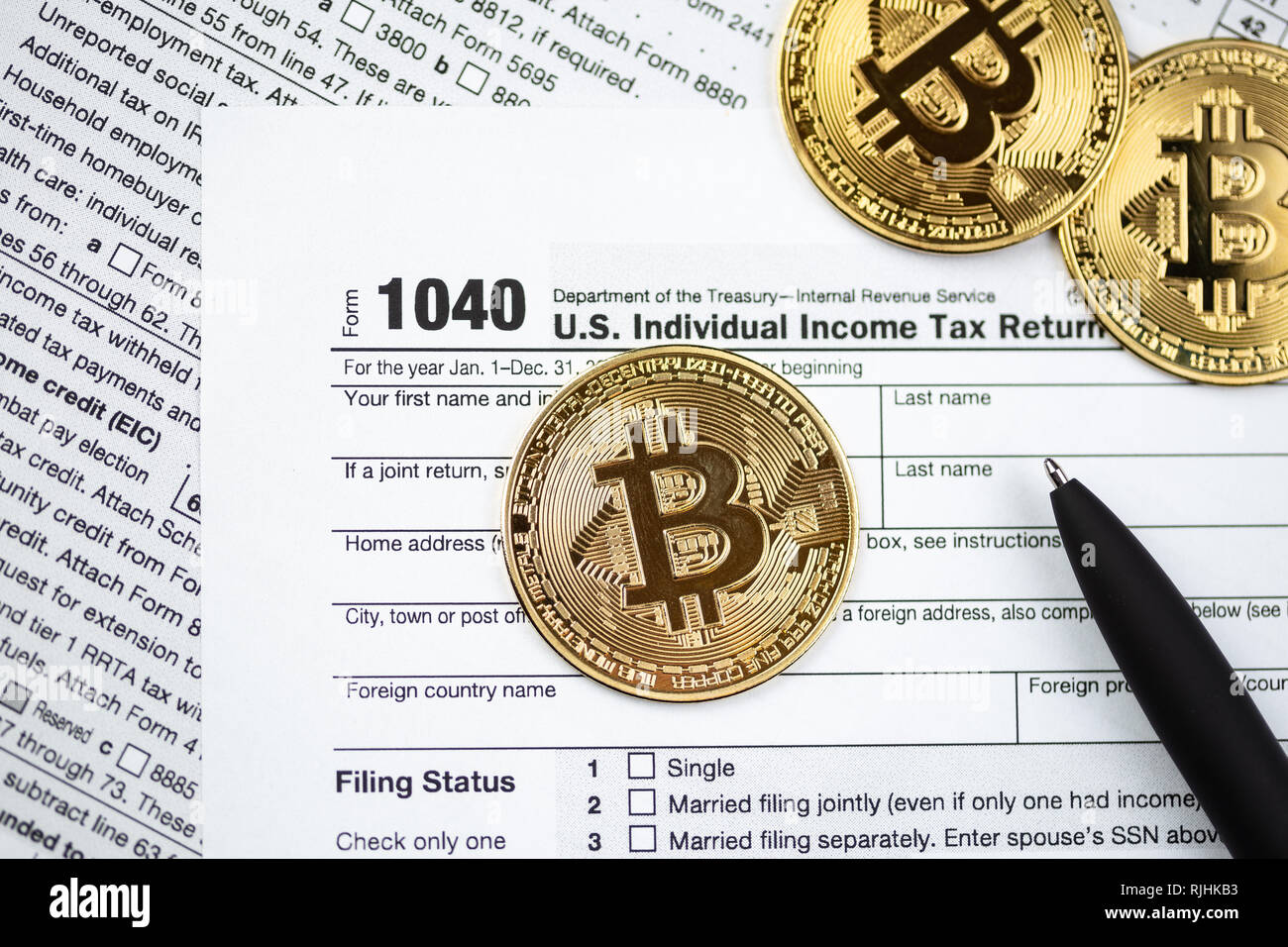 Bitcoins with US tax form 1040. Golden Bitcoin on tax form. Tax form pay concept Stock Photo