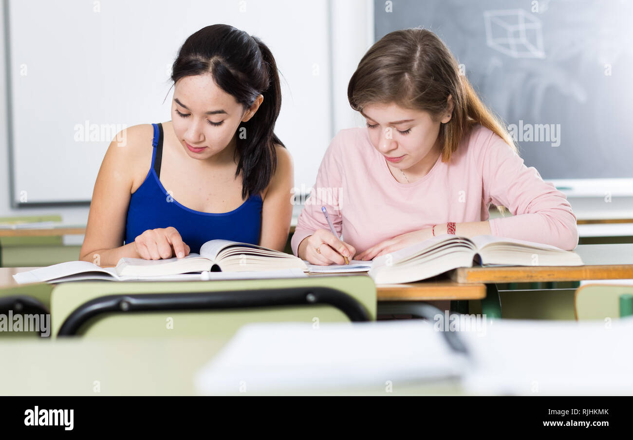 Smiling schoolgirls are learning at the desk in the class Stock Photo ...
