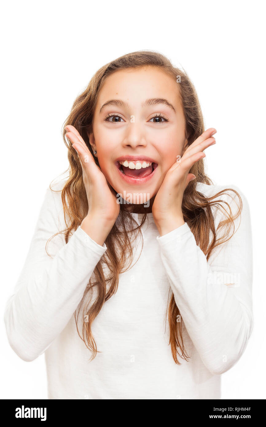Smiling young girl looking happily surprised with hands on her chin ...