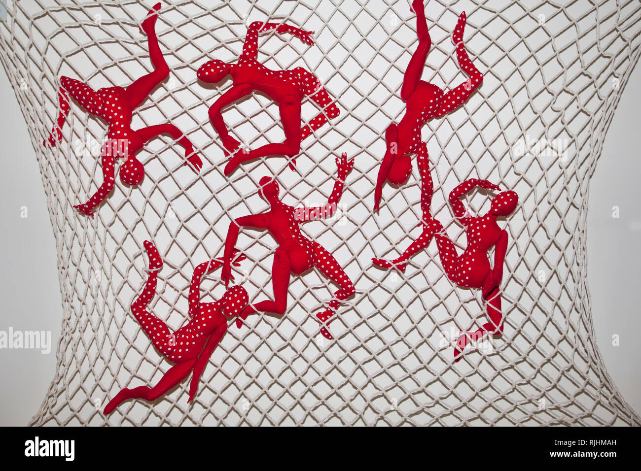 Artistic representation of articulated cloth figures entangled in a net of crocheted cotton in a fibre art construction by Judy M Tadman Stock Photo