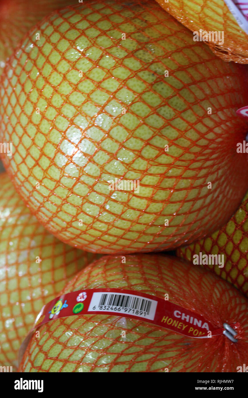 Display of orange in plastic net bag on a supermarket, close-up Stock Photo