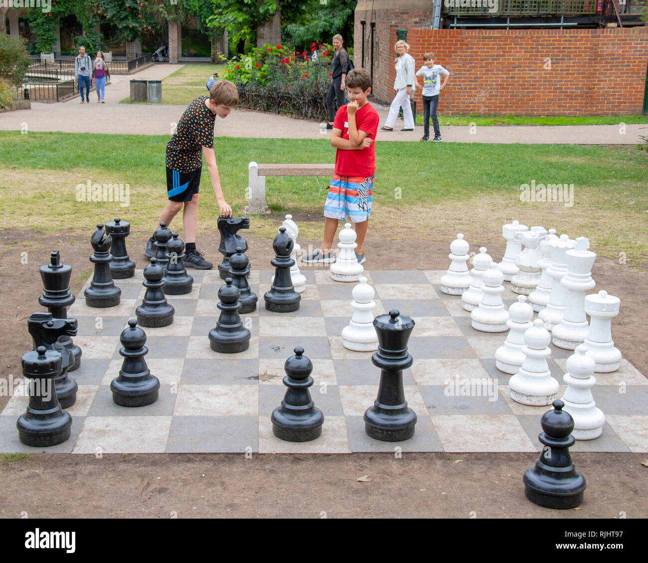 Two young boys playing outdoor chess in Holand Park in London, England Stock Photo