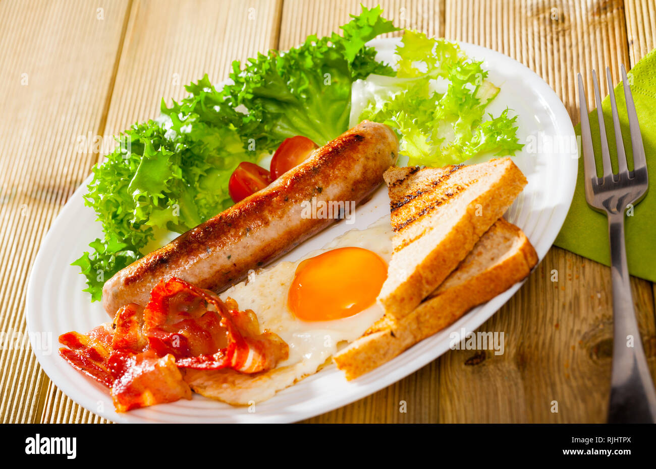 Highcalorific breakfast with fried sausage, scrambled eggs, toast and