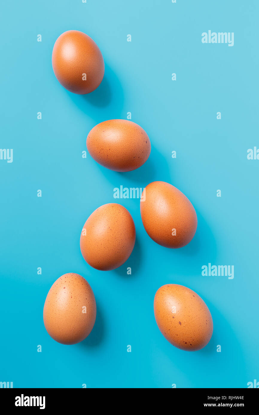 Six brown eggs on blue turquoise background, top view with copy space Stock Photo