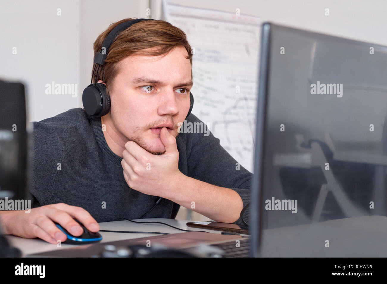 Worker looking at notebook at his desk. Business community background. Young businessmen sitting at the desk. Program developer working at office. Stu Stock Photo