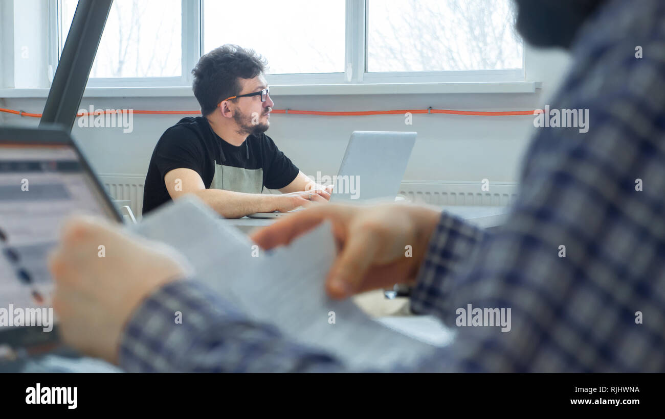 Business community background. Young businessmen sitting at the desk. Program developer working at office. Students at modern library. Business collea Stock Photo