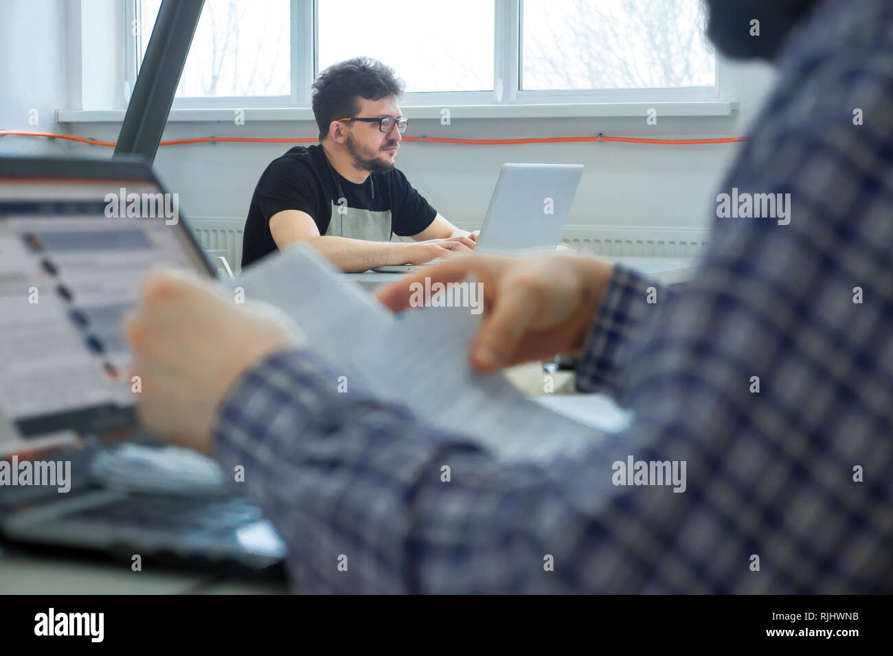 Young businessmen sitting at the desk. Business community working in open space office. Students at modern library. Business colleagues working at a b Stock Photo
