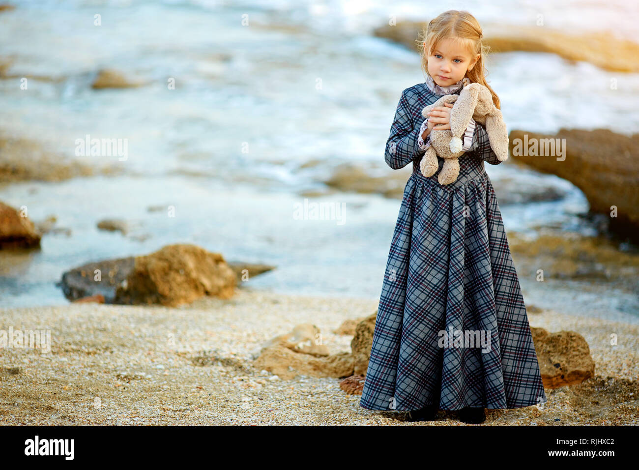 Girl in dress holding bunny toy in nature Stock Photo