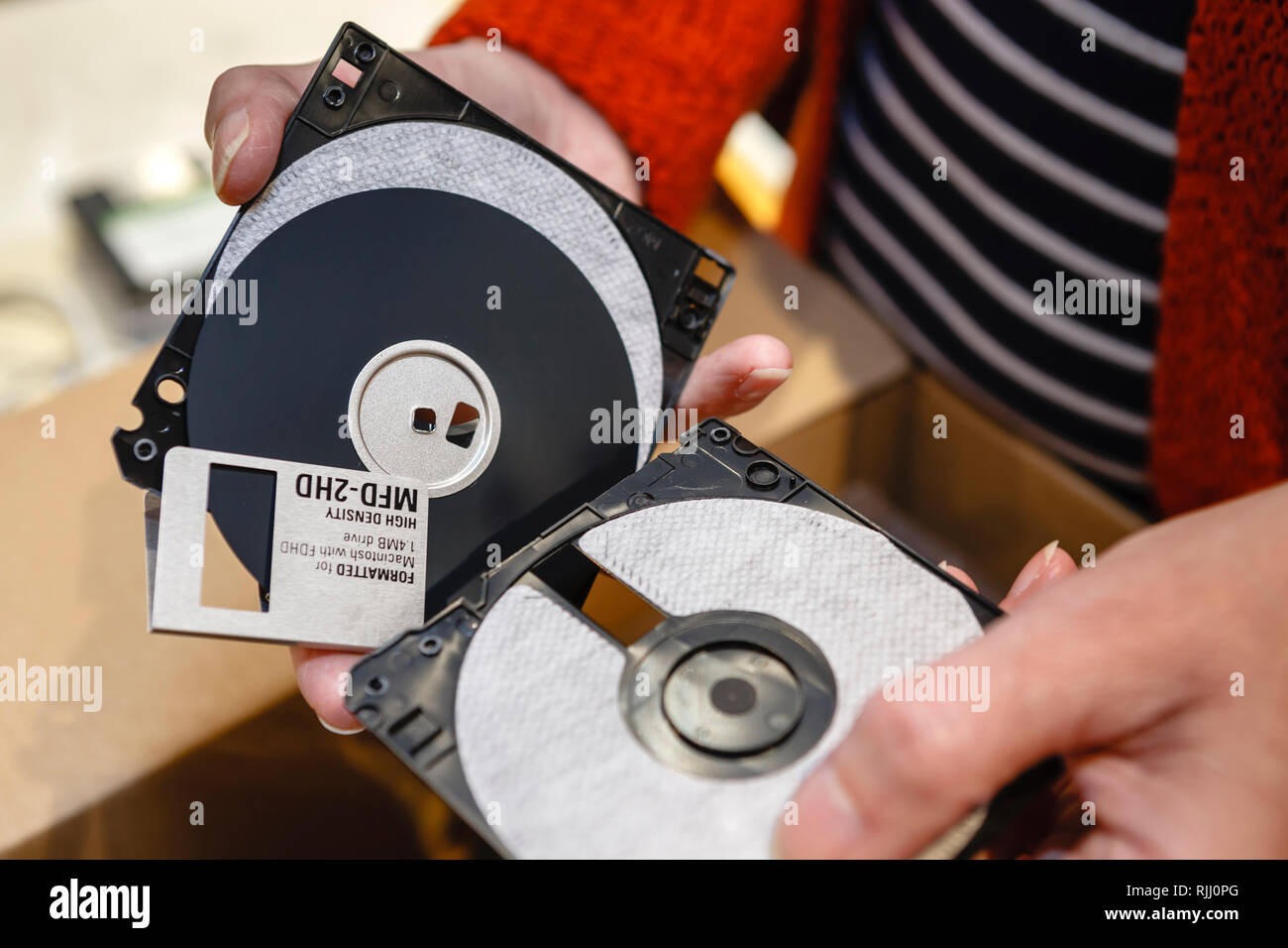 Cutting up old floppy disc with scissors to destroy information Stock Photo