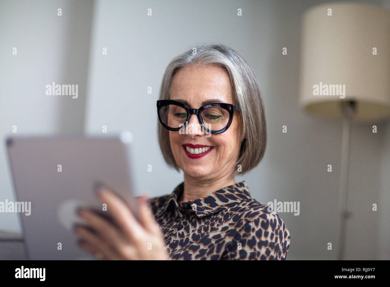 Mature adult female reading an ebook on a digital tablet Stock Photo