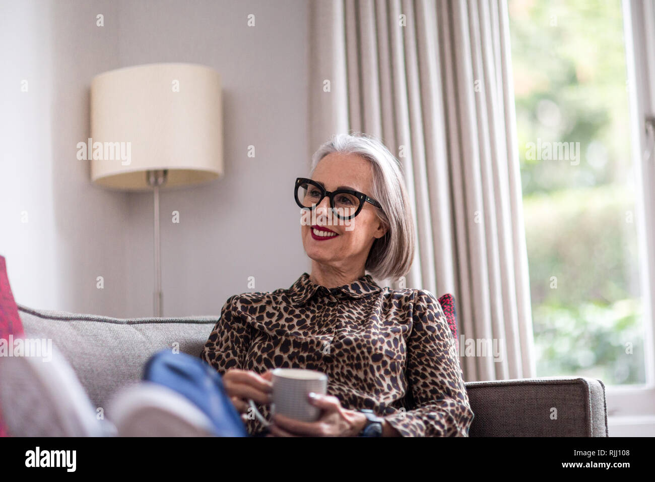 Mature adult female relaxing at home with a hot drink Stock Photo