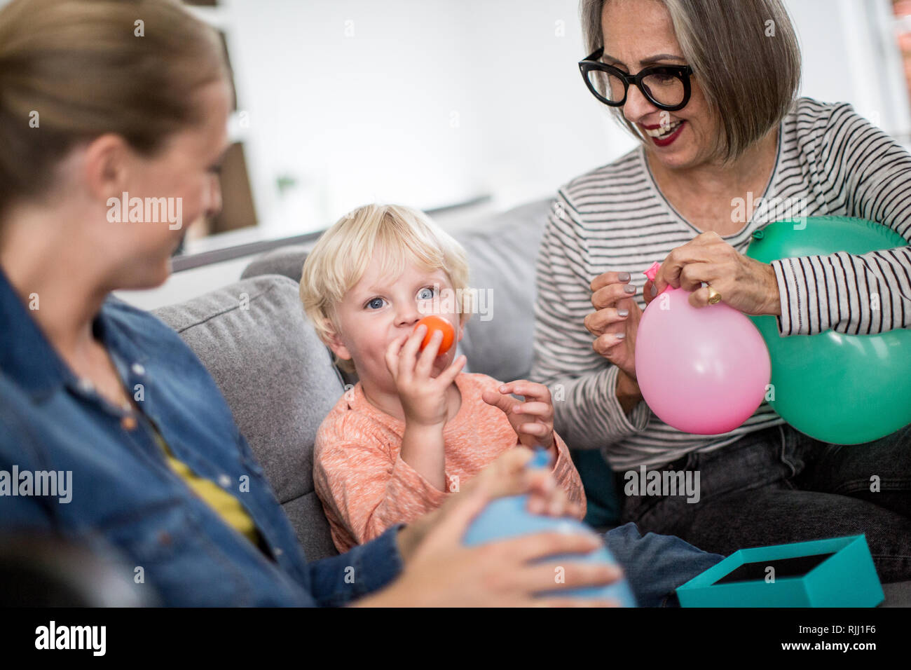 Boy blowing up birthday balloons with family Stock Photo Alamy