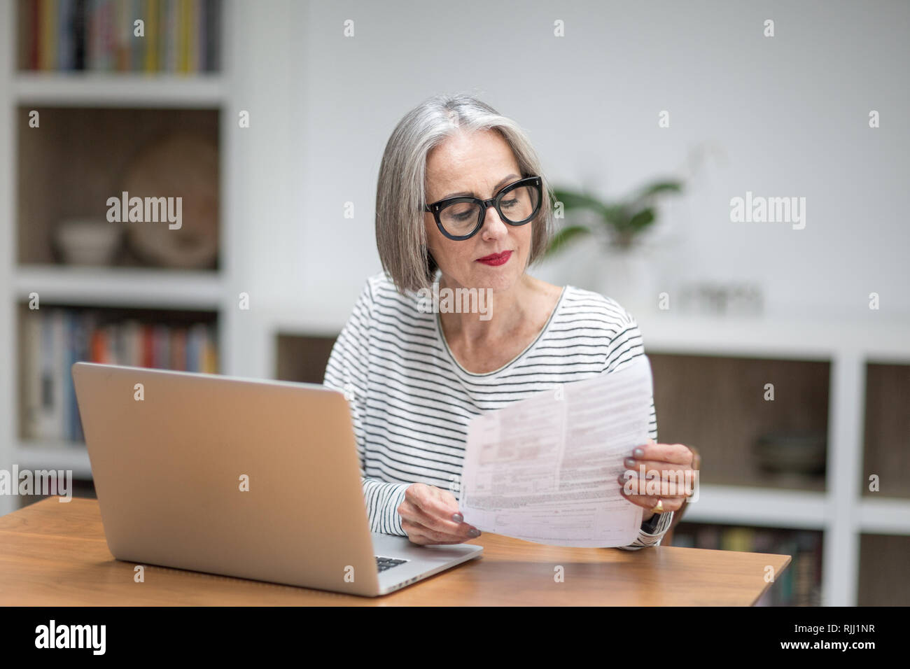 Mature adult female paying bill online using a laptop Stock Photo