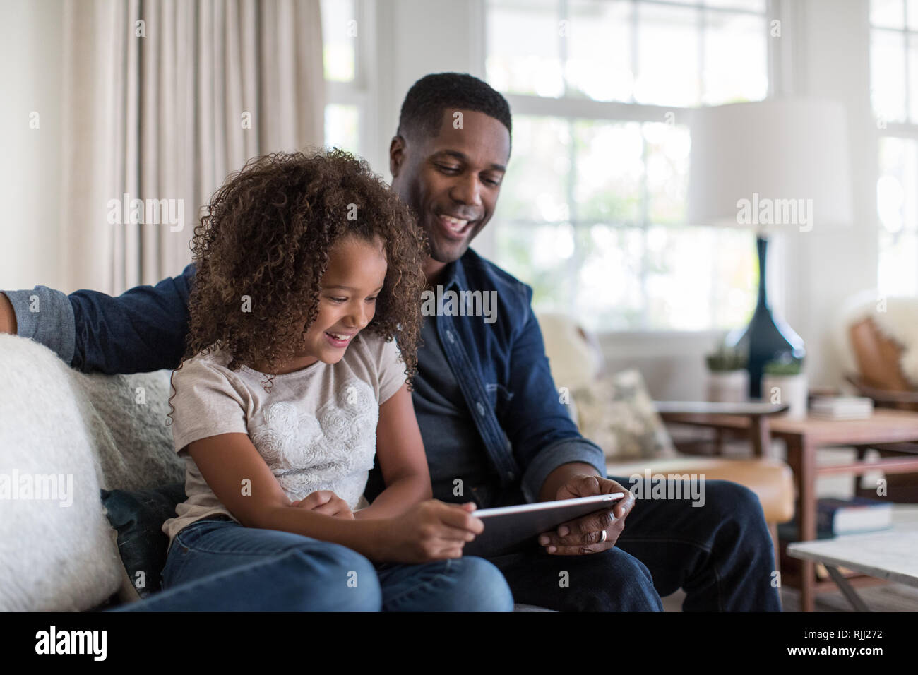 African American father and daughter using digital tablet together Stock Photo