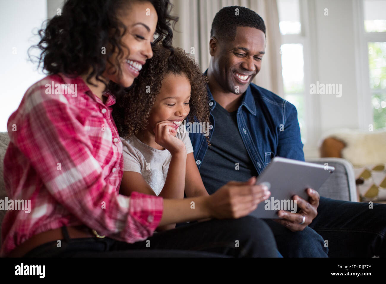 African American family watching video on digital tablet at home Stock Photo