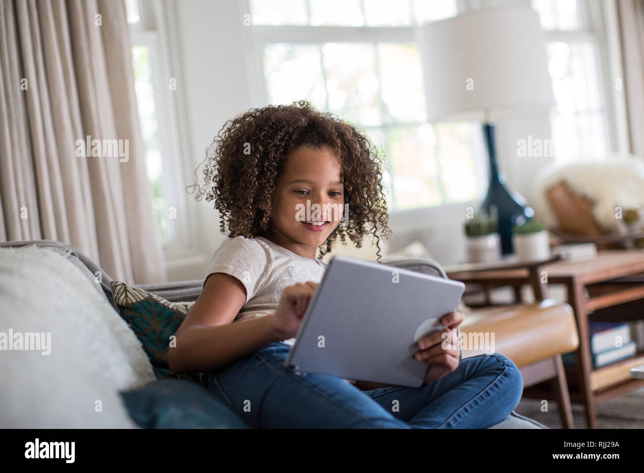 African American girl using digital tablet at home on sofa Stock Photo