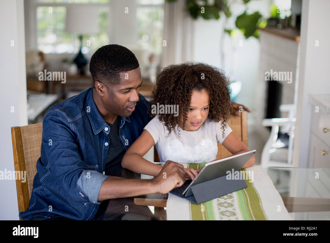 African American father helping daughter with homework using digital tablet Stock Photo