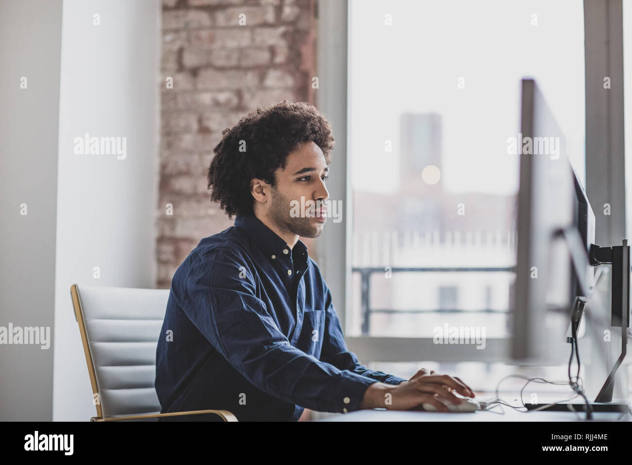 Male african american business executive working in an office on a desktop computer Stock Photo