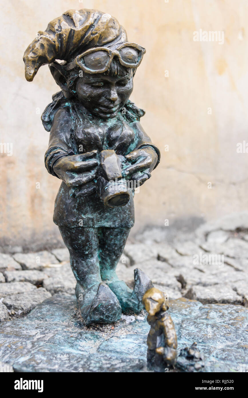 One of the brass gnomes (krasnale, krasnoludki), a photographer taking a photograph of a miniature gnome, in Wrocław, Wroklaw, Poland Stock Photo