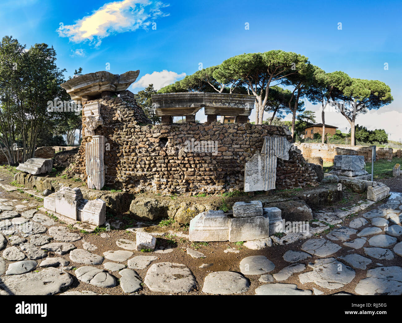 Archaeological excavations of Ostia Antica, the ruins of the Porta Romana and the cobblestones of the Decumanus Maximus Stock Photo