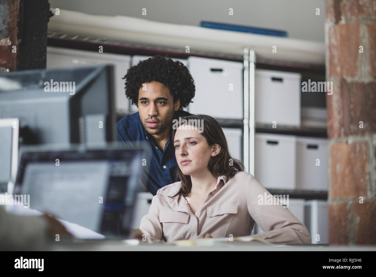 Coworkers looking at a desktop computer together Stock Photo