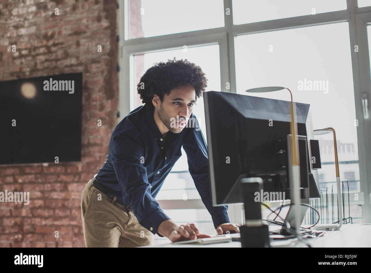 Male african american business executive standing and working on a desktop computer Stock Photo