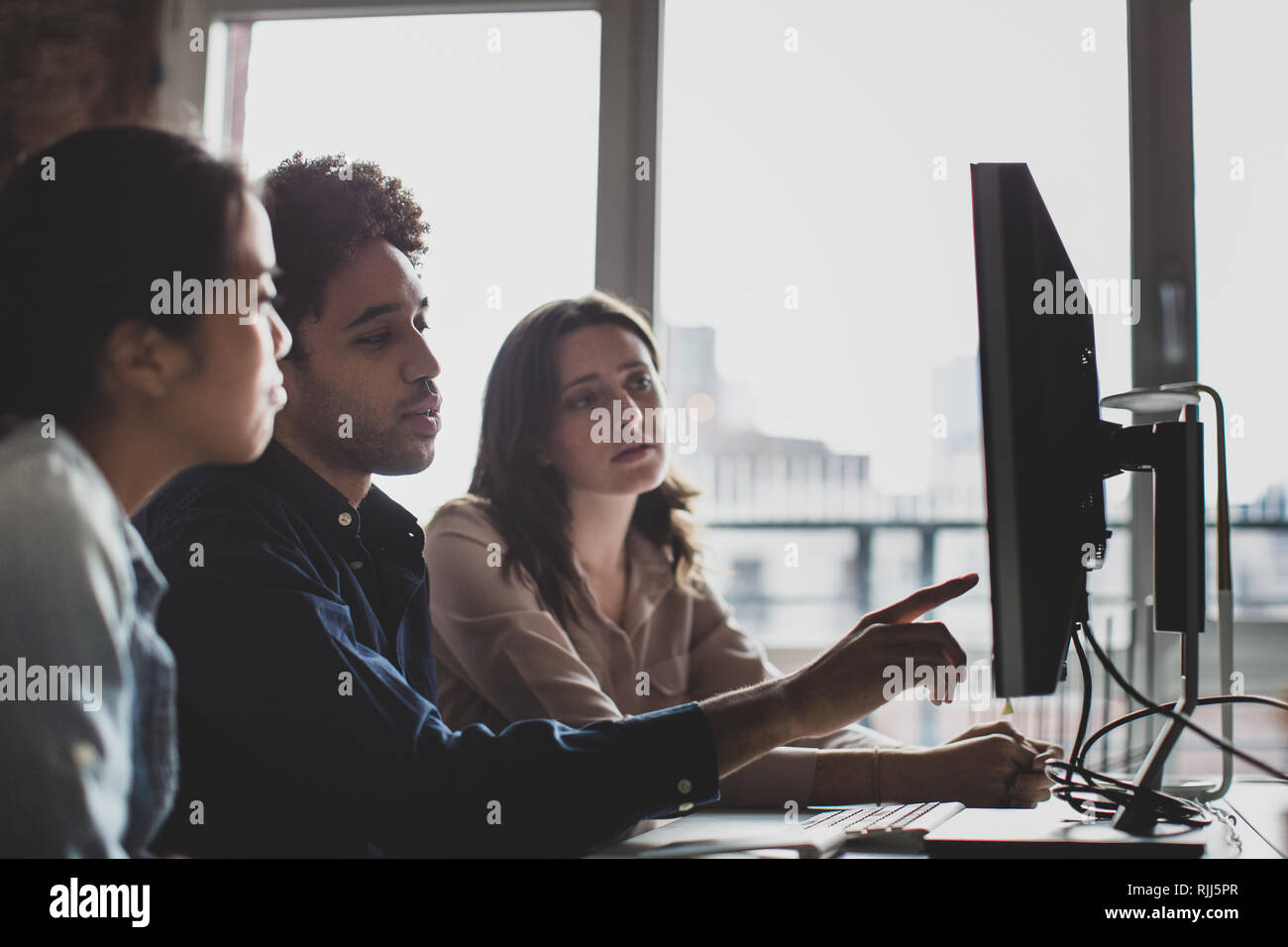 Coworkers looking at a desktop computer together Stock Photo