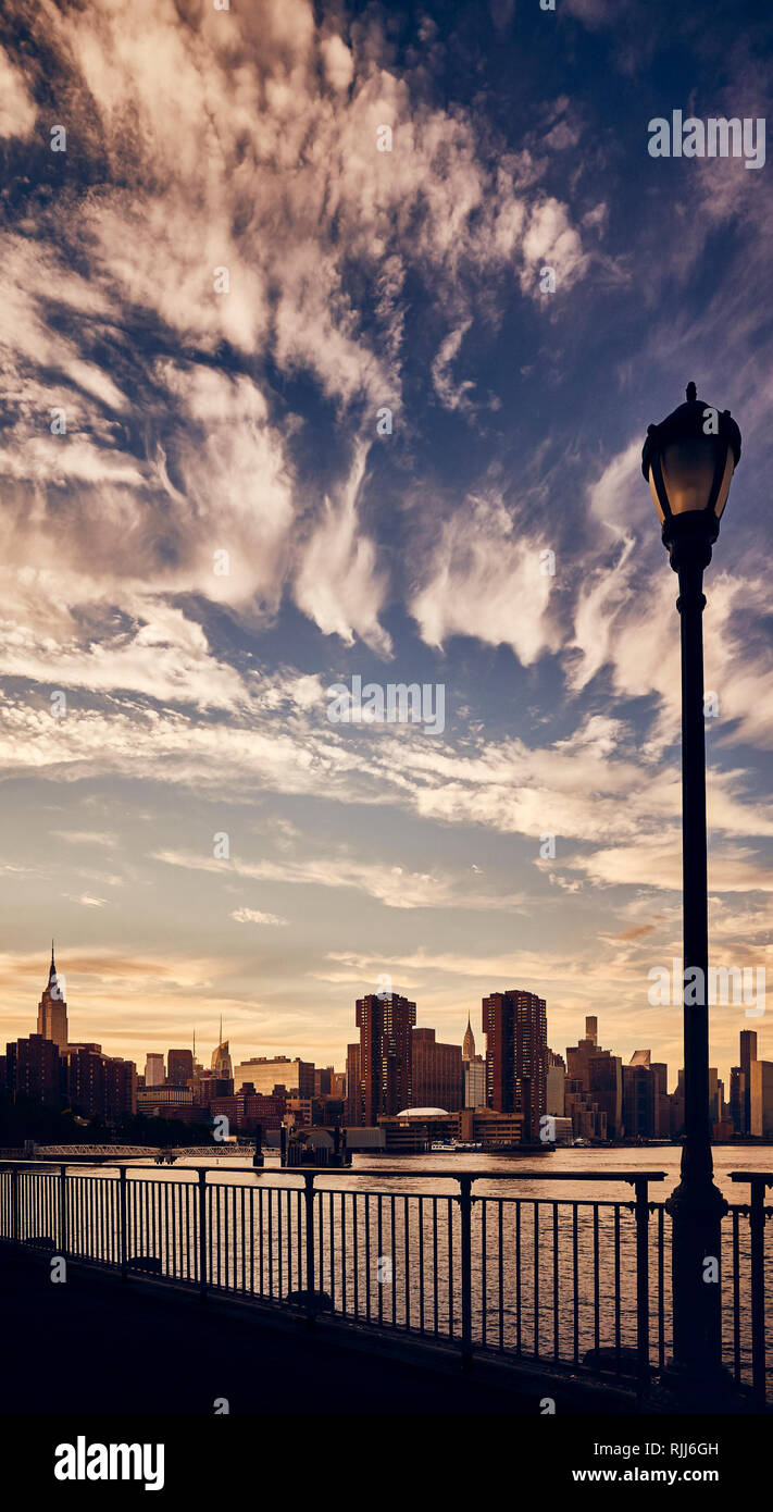 Manhattan skyline silhouette with dramatic cloudscape at sunset, color toned picture, New York City. Stock Photo