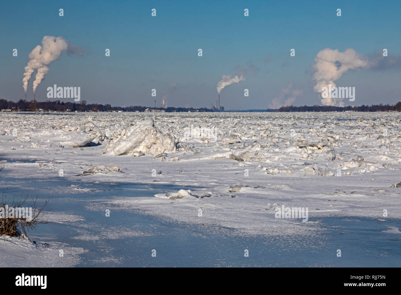 Marine City, Michigan - DTE Energy coal-fired power plants line the U.S. side (left) of the ice-filled St. Clair River. The Canadian side has mostly r Stock Photo