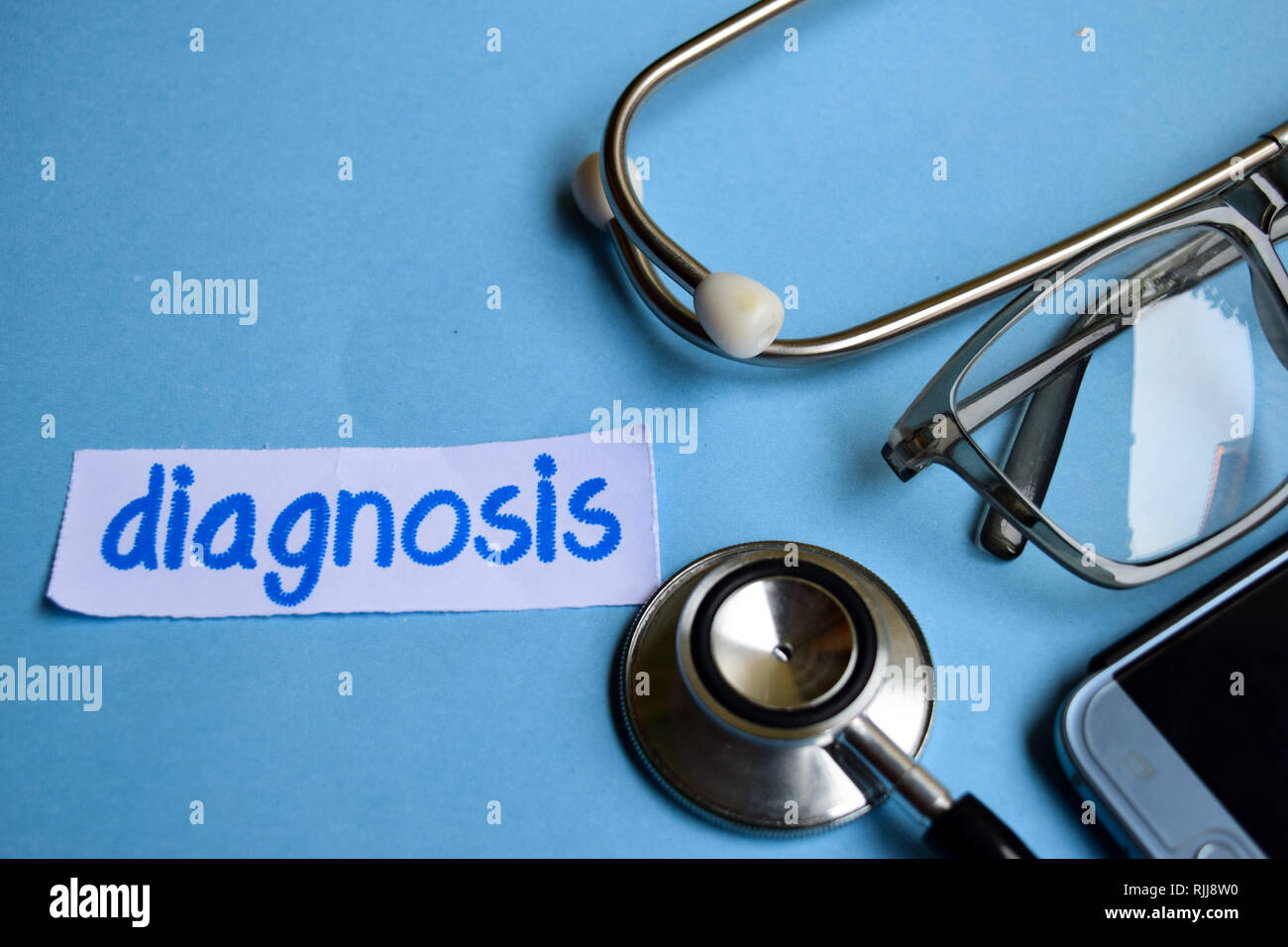 Conceptual image with Diagnosis inscription with the view of stethoscope, eyeglasses and smartphone on the blue background. Medical Conceptual. Stock Photo