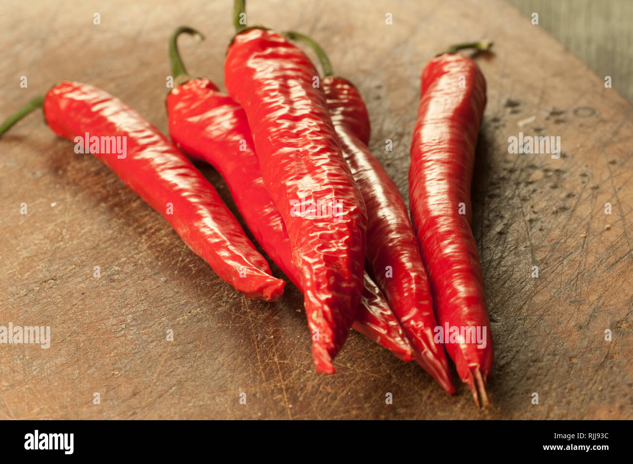 Red chilly peppers on a timber board Stock Photo - Alamy