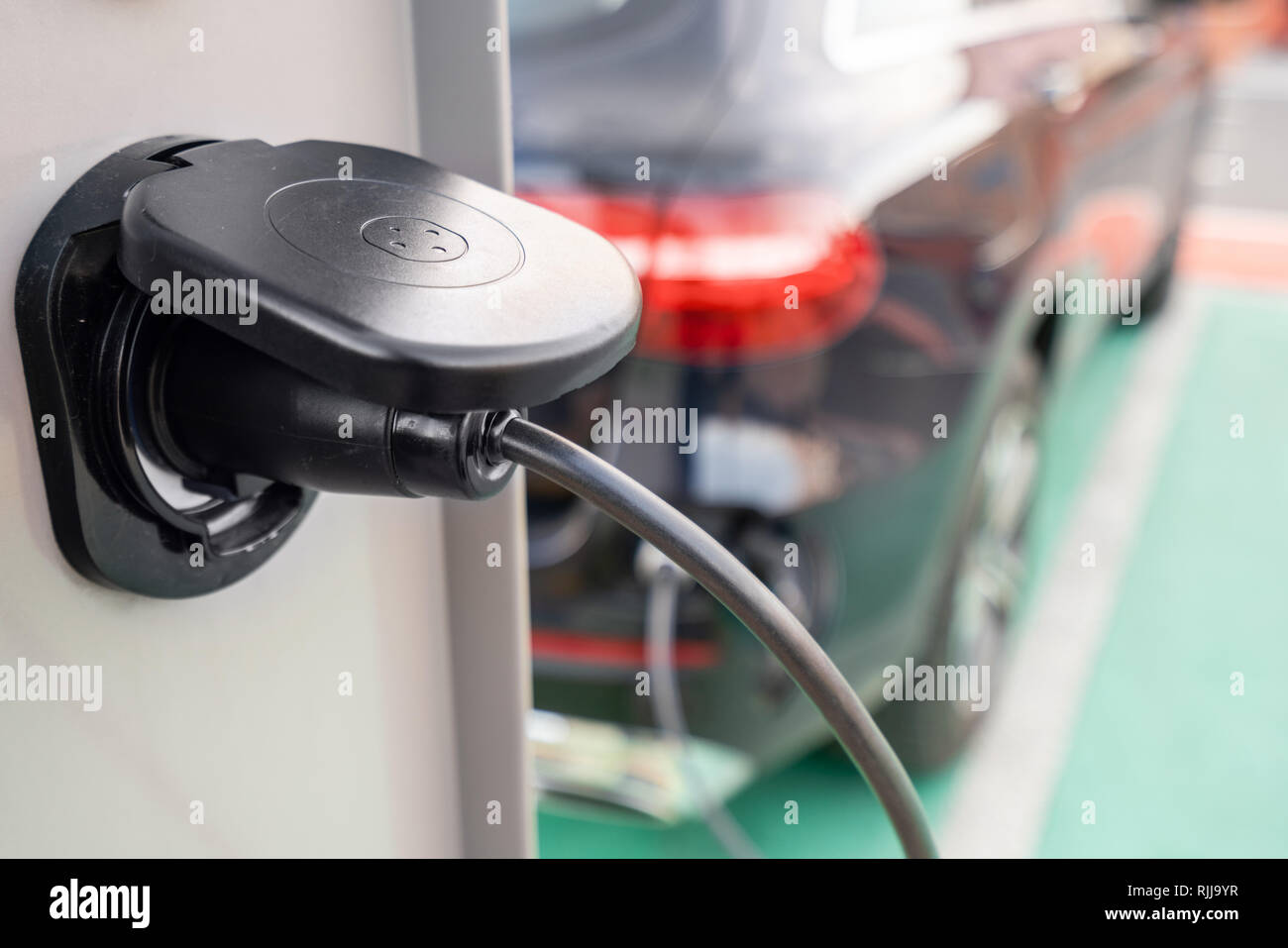 Close up of the power supply plugged into an electric car being charged. Electric car charging station. Concept of environmentally friendly engine Stock Photo