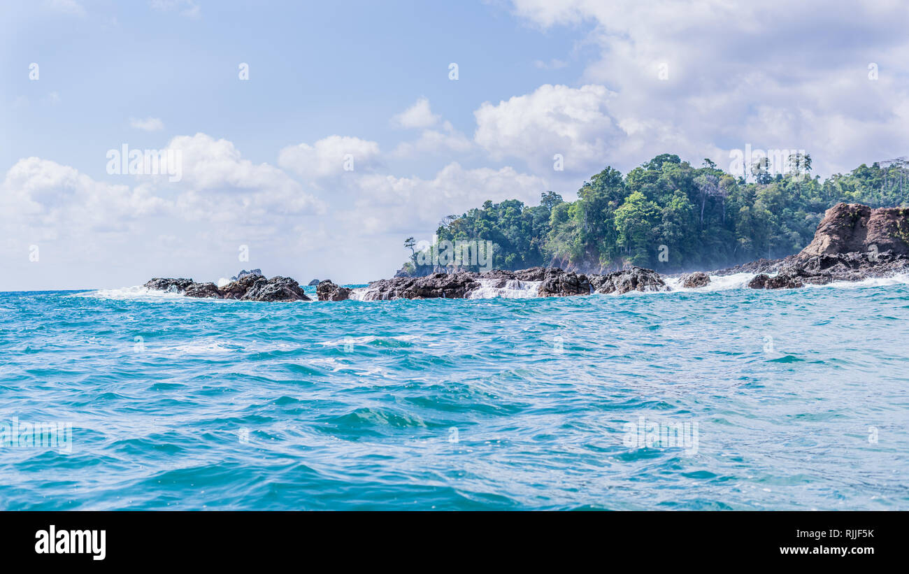 Artistic landscape photo of a tropical paradise. The beautiful but restless coastline on the background of rain forest of the Corcovado National Park. Stock Photo
