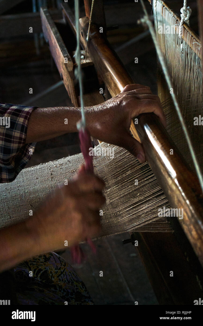Asian female hands operate a wooden loom weaving lotus thread, Inle Lake, Myanmar. Stock Photo